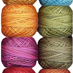 Puede incluir: Una colección de ovillos de hilo coloridos en varios tonos, incluyendo amarillo, beige, azul, naranja, verde, rosa, marrón, rojo y morado. Estos ovillos de hilo están bien enrollados y son adecuados para tejer o hacer ganchillo.