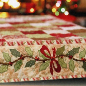May include: A rectangular Christmas table runner with a patchwork design in red, green, and tan. The bottom edge features a holly and berry garland with a red bow. The border has a candy cane stripe.