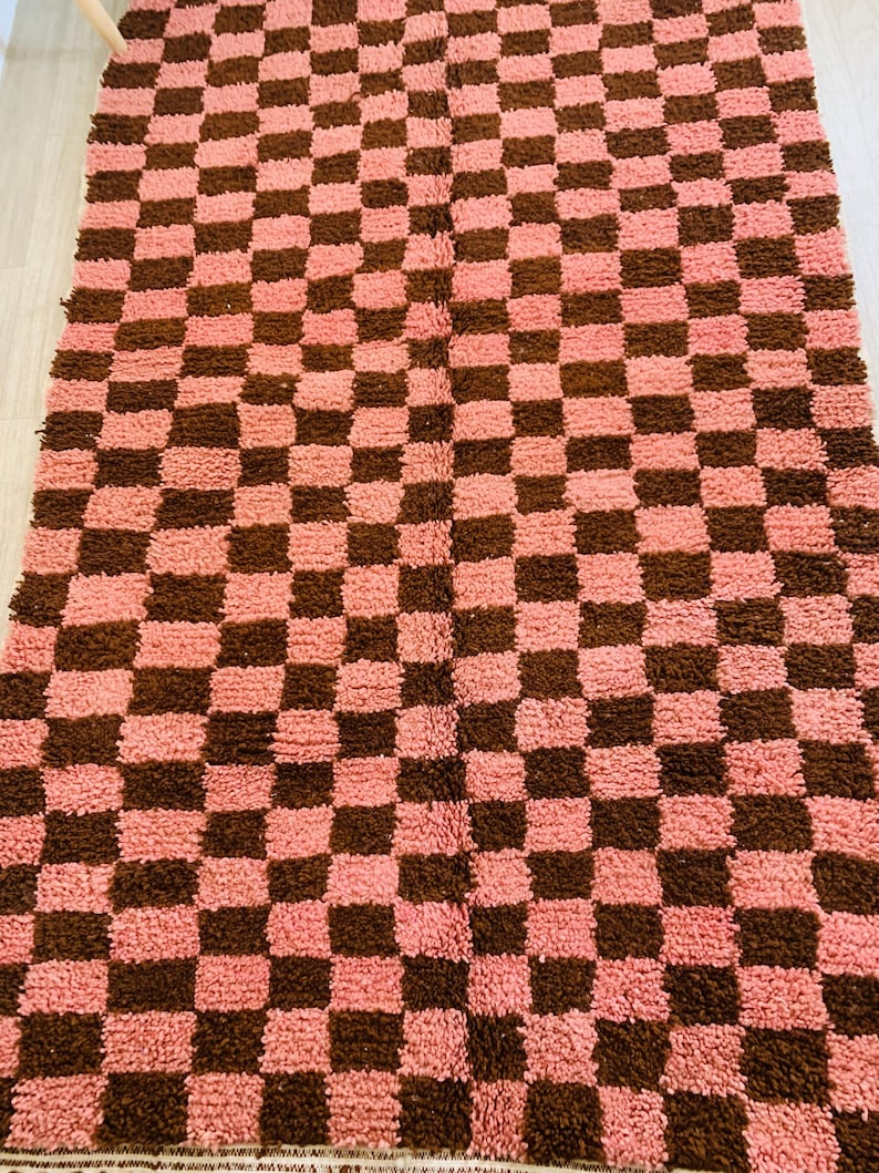 May include: A pink and brown checkered rug with a fluffy texture.