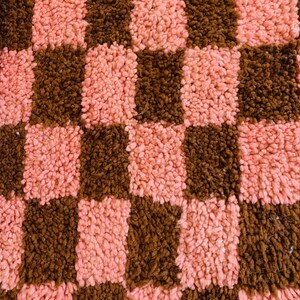 May include: A pink and brown checkered rug with a fuzzy texture.