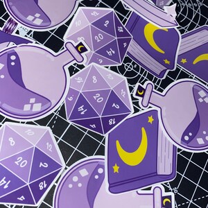 May include: Purple and white stickers featuring a variety of designs, including potion bottles, dice, and a book with a crescent moon. The dice are 20-sided and have numbers 12, 18, 20, 14, 4, 8, 10, 6, 9, 16, 2, and 1.