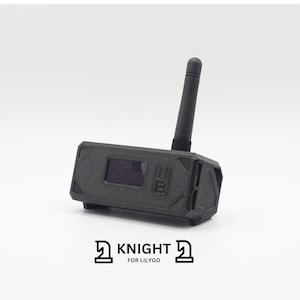 May include: A black, rectangular device with a small antenna. The device has a small screen and the text "UB" on the front. The device is labeled "KNIGHT FOR LILYGGO".