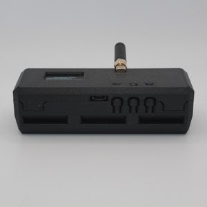 May include: A black rectangular device with a small antenna, a micro USB port, and four slots on the back. The device has the text "PGR" printed on the top.