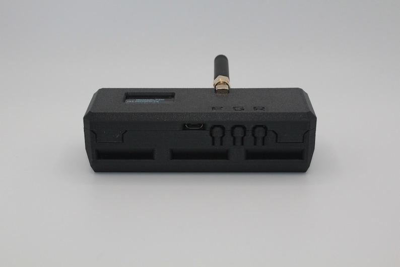 May include: A black rectangular device with a small antenna, a micro USB port, and four slots on the back. The device has the text "PGR" printed on the top.