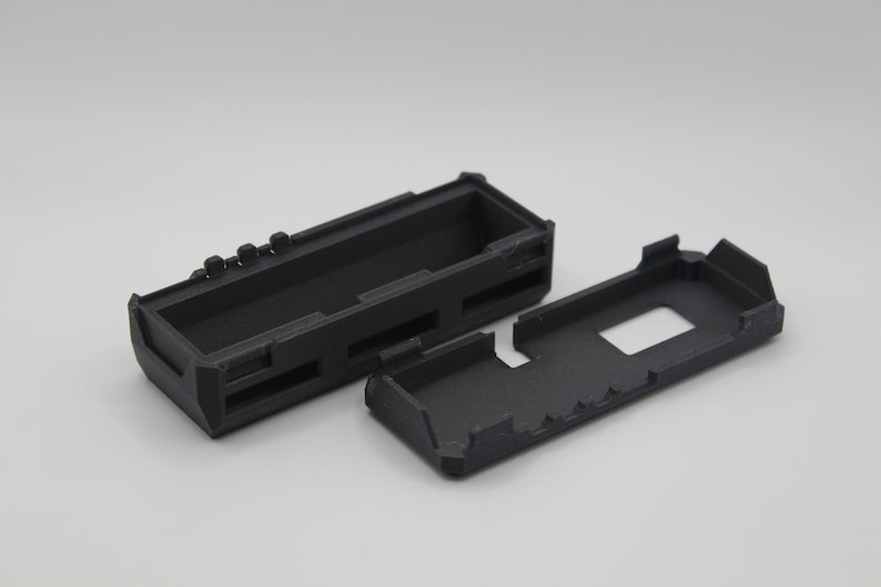 May include: Two black plastic cases, one open and one closed. The cases are rectangular and have a textured surface.