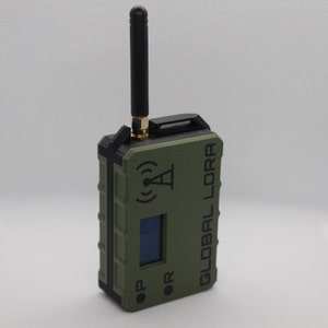 May include: A green and black handheld device with a black antenna, a small screen, and the text "GLOBAL LORA" printed on the side.