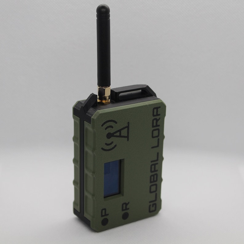 May include: A green and black handheld device with a black antenna, a small screen, and the text "GLOBAL LORA" printed on the side.
