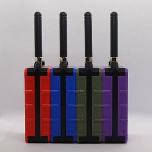May include: Four wireless transmitters with black antennas, each with a different colored case: red, blue, green, and purple.