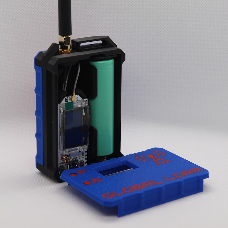 May include: A blue and black device with a removable lid. The device has a small screen and a battery inside. The lid has the text "GLOBAL Lora" and a symbol of an antenna.