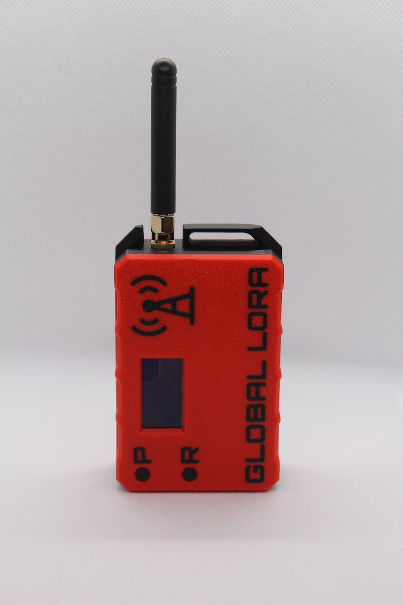 May include: A red and black handheld device with a black antenna, a small screen, and the text "GLOBAL LORA" printed on the side. The device has two buttons labeled "OP" and "OR".