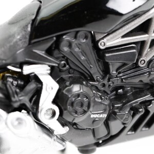 May include: Close-up of a black Ducati motorcycle engine. The engine features intricate details, including silver accents, a visible Ducati logo, and various mechanical components. The image highlights the motorcycle's design and engineering.