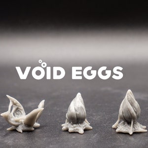 May include: Three grey, 3D printed, organic-shaped objects resembling eggs with a rough, textured surface. The objects are labeled "VOID EGGS".