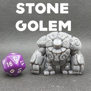 May include: A gray stone golem miniature with a detailed, textured surface. The golem has a round head with a face sculpted with swirls and a wide, toothy grin. The miniature is standing next to a purple 10-sided die.