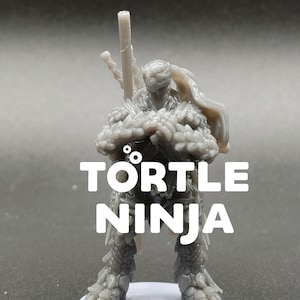 May include: A gray, 3D-printed miniature of a Tortle Ninja, a fantasy character. The figure is detailed with textured armor, a weapon, and a flowing cape. The text "TORTLE NINJA" is displayed in white block letters.