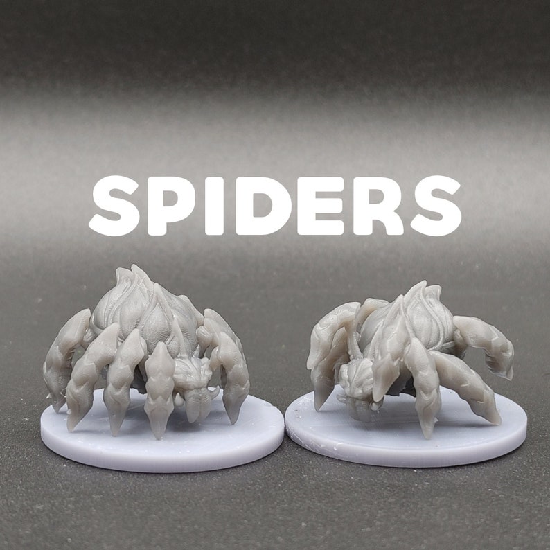 Może przedstawiać: Dwie szare, szczeg&oacute;łowe figurki pająk&oacute;w z tworzywa sztucznego na małych, okrągłych, szarych podstawkach. Słowo "SPIDERS" jest nadrukowane białymi literami nad figurkami.