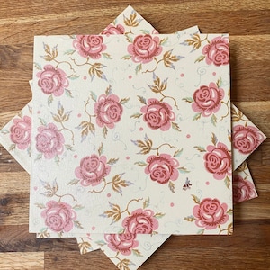 May include: A set of three vintage floral patterned paper napkins with pink roses and a white background.
