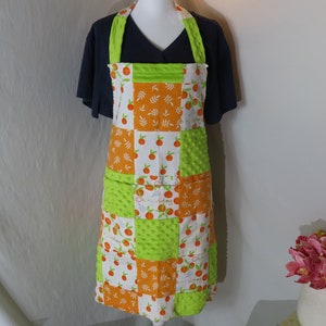 May include: A green and orange patchwork apron with a pocket and the text "Oh my darling" on the front.