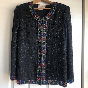 May include: A black beaded jacket with a colourful beaded trim. The trim features red, green, blue and silver beads.