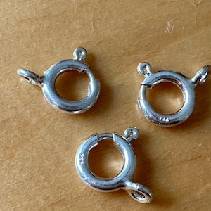 Può includere: Tre anelli di salto argentati con chiusura a molla. Gli anelli hanno un diametro di circa 2,5 cm.