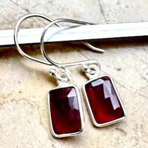 Peut inclure: Une paire de boucles d'oreilles en argent avec des gouttes de pierres précieuses rouges rectangulaires.