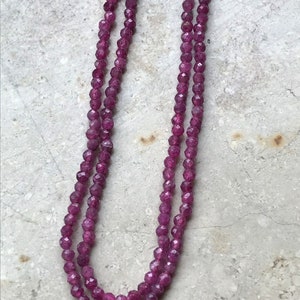 Könnte beinhalten: Eine doppelreihige Halskette aus kleinen, facettierten, rosafarbenen Rubinperlen.