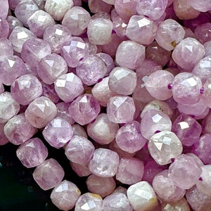Könnte beinhalten: Eine Strähne facettierter Amethystperlen in Schattierungen von Hellviolett und Weiß. Die Perlen sind alle ungefähr gleich groß und gleich geformt und haben eine glatte, polierte Oberfläche.