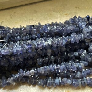 Op de afbeelding: Een streng blauwe kyanite chip kralen. De kralen zijn onregelmatig van vorm en hebben een natuurlijke, ruwe textuur.