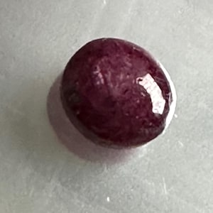 Könnte beinhalten: Ein tiefroter Edelstein mit einer glatten, polierten Oberfläche.