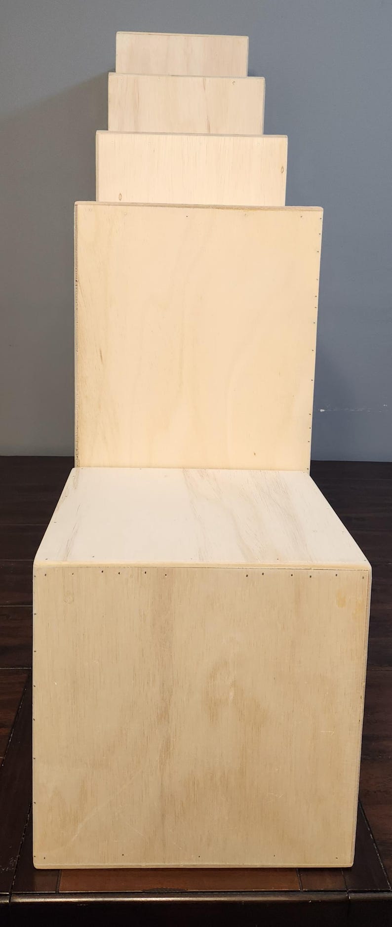 Puede incluir: Una pila de seis cajas de madera sin terminar, cada una con una superficie lisa de color marr&oacute;n claro. Las cajas est&aacute;n apiladas en forma de pir&aacute;mide, con la caja m&aacute;s grande en la parte inferior y la m&aacute;s peque&ntilde;a en la parte superior. Las cajas est&aacute;n hechas de madera contrachapada y tienen una veta de madera natural.