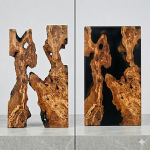 May include: Two wooden sculptures with a natural, organic design. One is a free-form shape, and the other is a rectangular block with a black resin filling. The wood has a warm brown color with lighter streaks and knots.