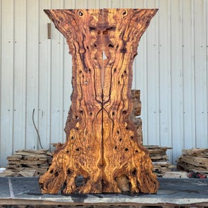 May include: A large, vertical live-edge wood slab featuring a symmetrical book-matched grain pattern with rich brown and golden yellow swirls, knots, and organic textures. The wood surface displays handwritten markings indicating 30 inches in width.