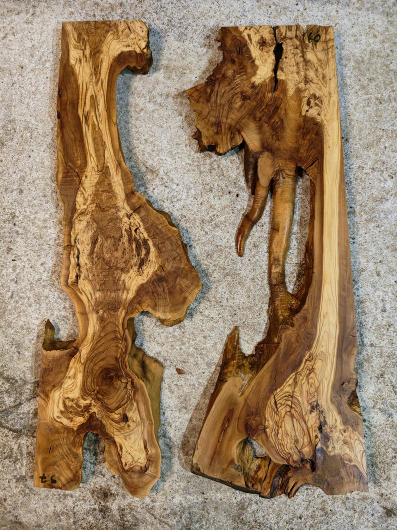 May include: Two irregularly shaped, unfinished wooden slabs with natural edges. The wood grain features a mix of light and dark brown tones, with visible knots and unique patterns. The slabs are likely for woodworking projects.