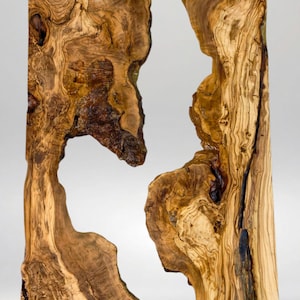 May include: Two irregularly shaped wooden slabs with a natural, organic aesthetic. The wood grain is prominent, showcasing a mix of light and dark brown tones. The slabs have a unique, open design with a cutout in the center. The text "58/52/180" is visible.