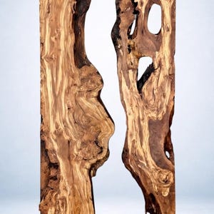 May include: Two vertical wooden slabs with a natural, organic aesthetic. The wood features a mix of light and dark brown tones, with intricate grain patterns and unique, irregular shapes. The slabs have a raw, unfinished appearance, showcasing the natural beauty of the wood.