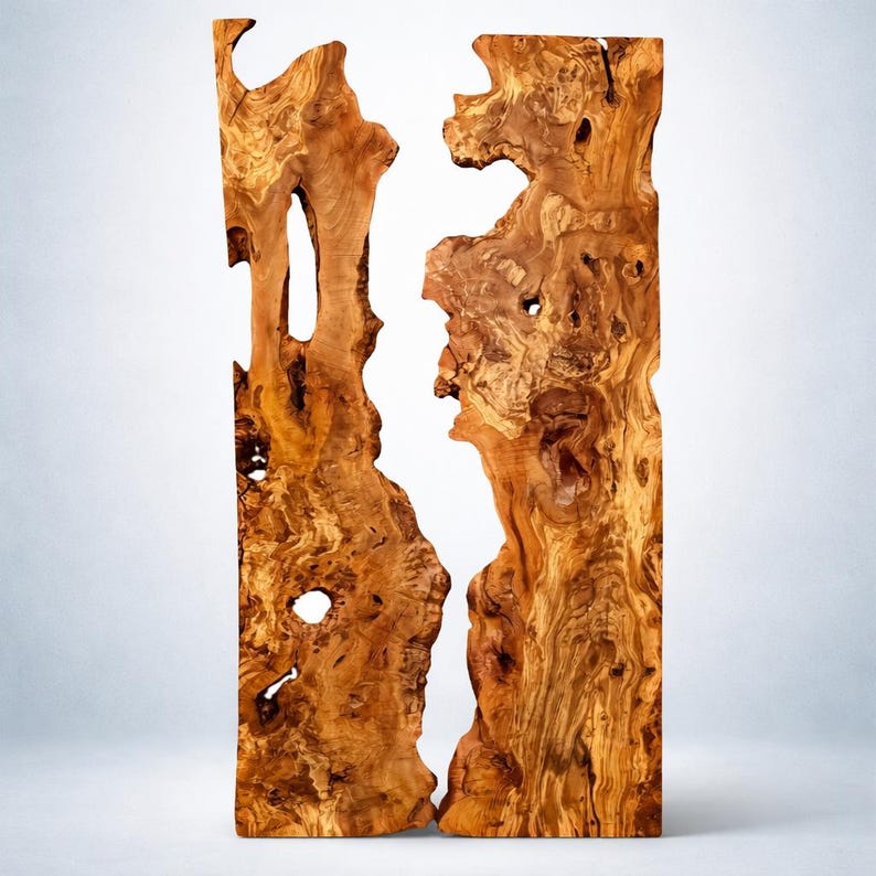 May include: A vertical wooden slab with a natural, organic shape. The wood has a warm, brown color with intricate grain patterns and knots. A white, irregular void runs through the center, creating a striking contrast. The wood appears to be a decorative piece.