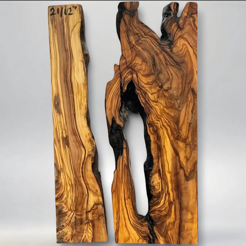 May include: Two pieces of olive wood, one with the text "21/12" in the upper left corner. The wood has a natural grain pattern with shades of brown and yellow. One piece has a large, dark void.