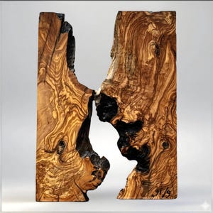 May include: A handcrafted wooden sculpture with a unique, organic design. The sculpture is made from a light brown wood with dark brown and black accents. The wood grain is visible, adding to the natural aesthetic. The sculpture has a distinctive shape with a central void.
