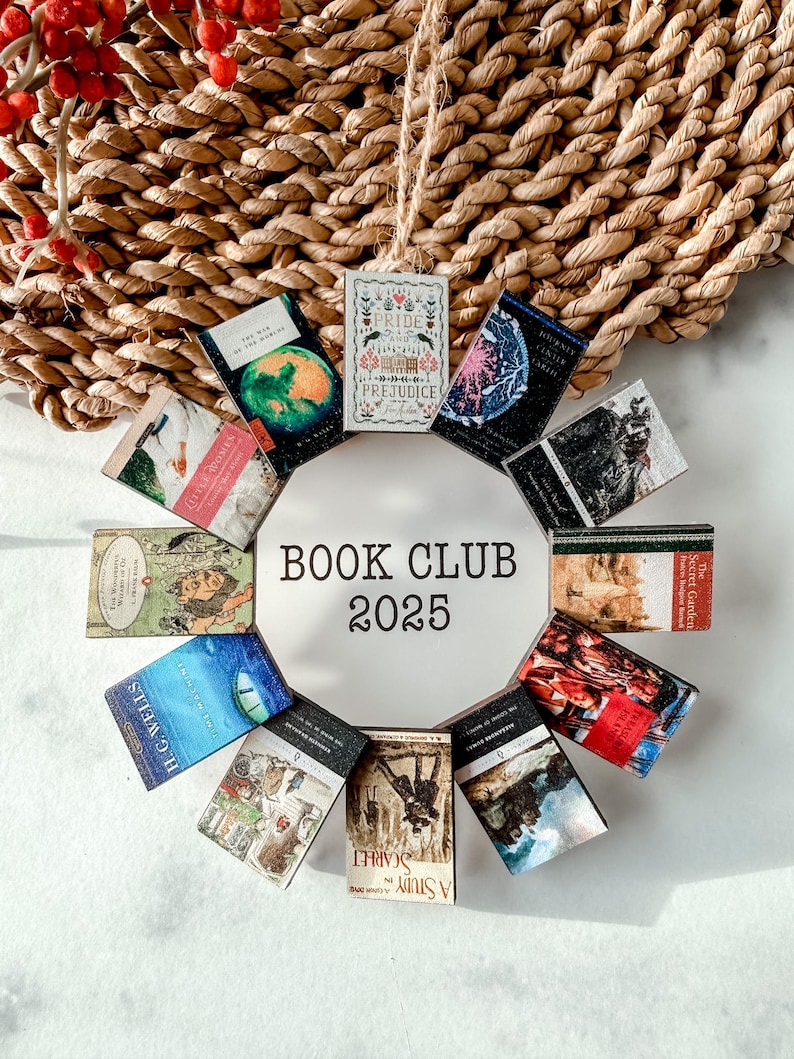 May include: A circular book club ornament featuring miniature book covers arranged around a white circle. The text "BOOK CLUB 2025" is printed in black. The ornament is set against a woven background with red berries.