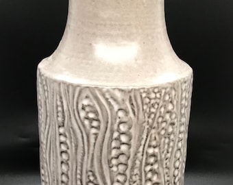 May include: A white ceramic vase with a textured, wavy design. The vase has a wide base and a narrow neck.