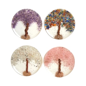 May include: Four round resin coasters with a copper wire tree design. Each coaster features a different colour of crushed gemstones: amethyst, multi-coloured, white, and rose quartz.