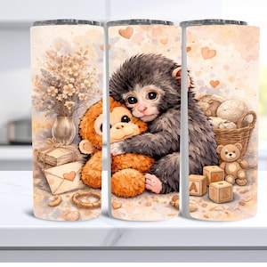 May include: A tumbler featuring a watercolor design of a monkey hugging a stuffed animal. The design includes a vase of flowers, a teddy bear, wooden blocks, and a basket of yarn balls. The background has heart shapes.