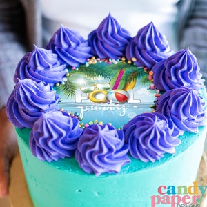 May include: A turquoise cake with purple frosting and a round edible image on top. The image is of a pool party scene with palm trees, sunglasses, a beach ball, and the text "Pool Party".