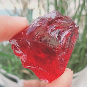 May include: A large, red, faceted crystal with a smooth, glassy surface.