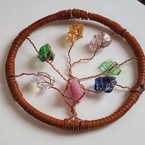 Puede incluir: Una escultura de árbol de alambre con una base de madera marrón y piedras de vidrio y cristal de colores que cuelgan de las ramas.