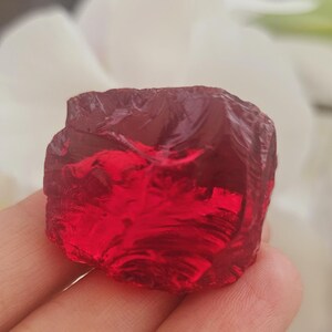 May include: A large, deep red, faceted, crystal gemstone.