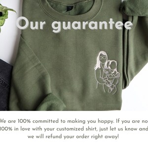 Puede incluir: Sudadera verde oliva con el texto "Our guarantee" y una ilustraci&oacute;n bordada de una madre y un ni&ntilde;o. La sudadera se combina con unos vaqueros negros y una peque&ntilde;a planta.