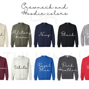 Puede incluir: Una muestra de colores de cuello redondo y sudaderas con capucha, incluyendo arena, verde militar, azul marino, negro, gris deportivo, granate, blanco, azul real, gris oscuro y rojo. El texto "Crewneck and Hoodie colors" est&aacute; arriba.