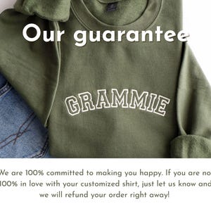 K&ouml;nnte beinhalten: Ein olivgr&uuml;nes Sweatshirt mit dem Wort "GRAMMIE" in wei&szlig;en, gebogenen Buchstaben. Das Sweatshirt liegt neben einer Jeans. Der Text "Our guarantee" steht oben.