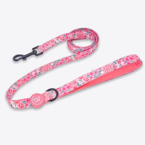 May include: Pink dog lead with a floral pattern and a black metal clip. The lead has a pink Wild Cub logo on the handle.