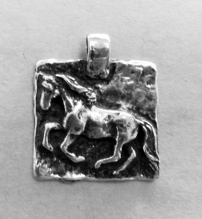 May include: A silver pendant featuring a detailed, textured design of a horse running. The pendant has a square shape with a loop at the top for attaching a chain.